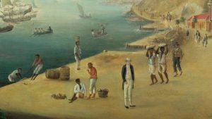 Image of the harbor of Gustavia, the capital of St Barth with Black men carrying commodities or working while one man stands idly
